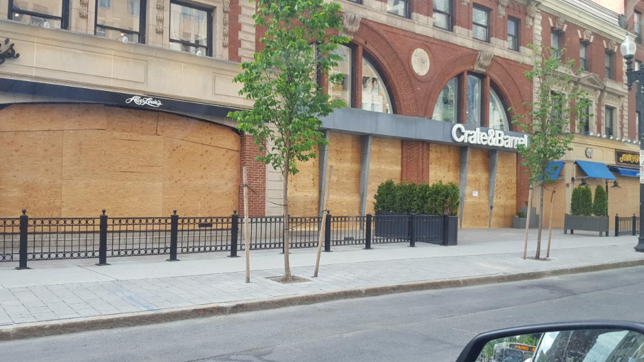 Crate and barrel store front with boarded up windows.